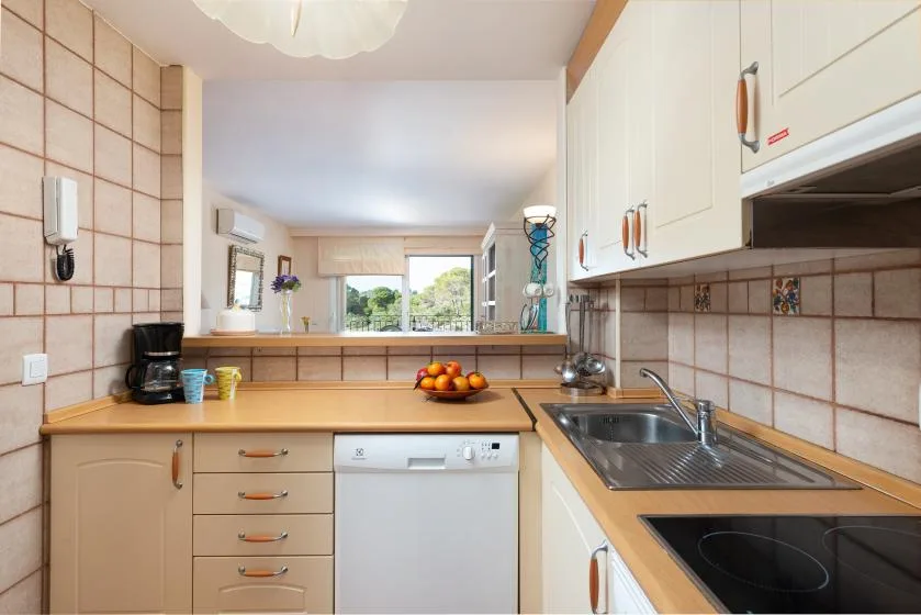 A kitchen with countertop appliances, a sink, and a window overlooking greenery.
