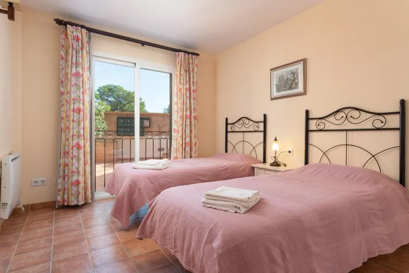 A bedroom with two beds, floral curtains, and a glass door opening to a balcony.