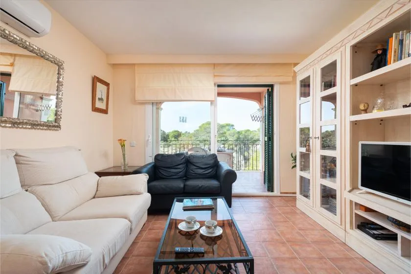 A living room with seating, a coffee table, and a glass door opening to a balcony.