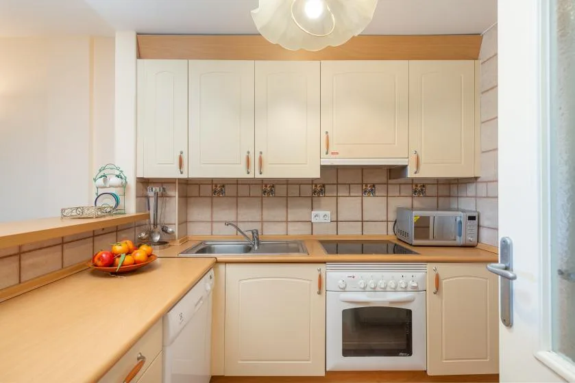 A bright kitchen with light cabinets, a countertop, and a built-in oven.