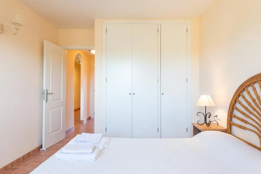 A bedroom with a white bed and built-in closets.