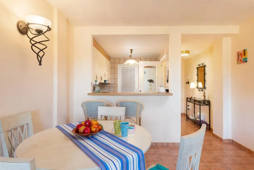 A dining area with a round table and a view through to the kitchen.