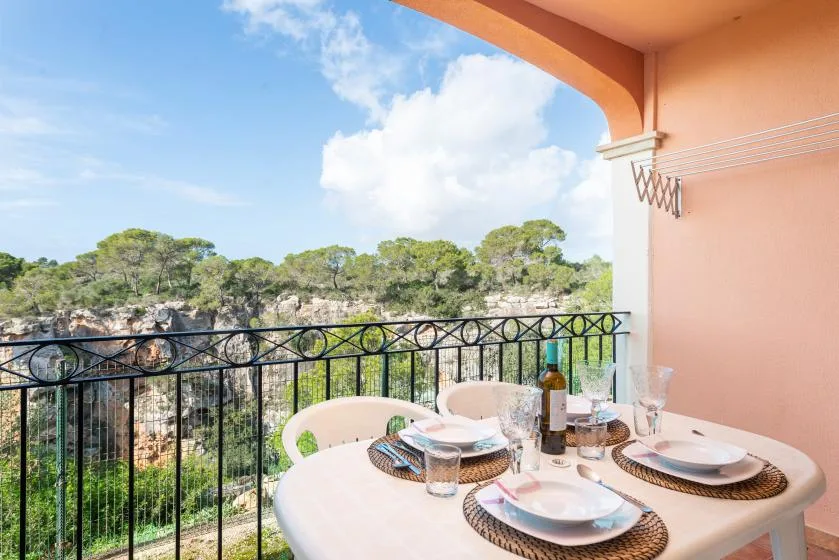 A balcony dining area overlooks green trees and a rocky landscape.