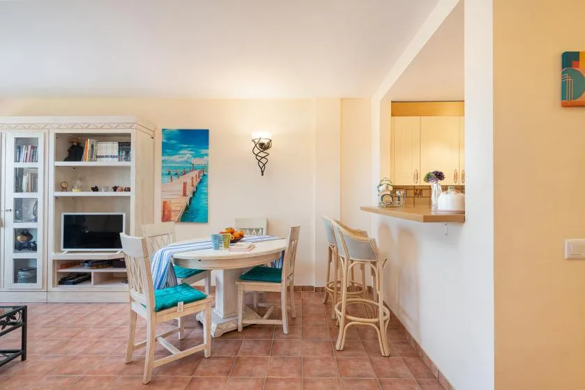 A dining area with a table and chairs beside a built-in kitchen counter.