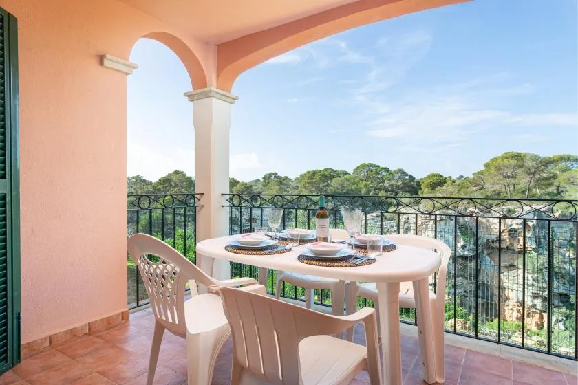 A covered terrace dining area overlooks trees beyond a black railing.