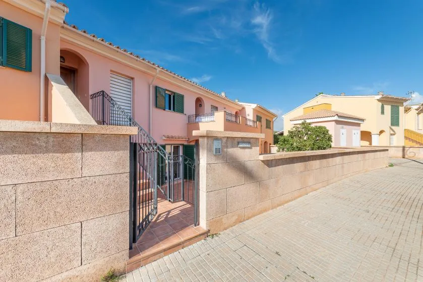 A row of peach-colored homes lines a paved walkway behind a low wall.