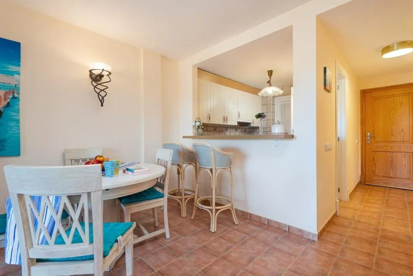 A dining area with a table and chairs beside a kitchen pass-through.
