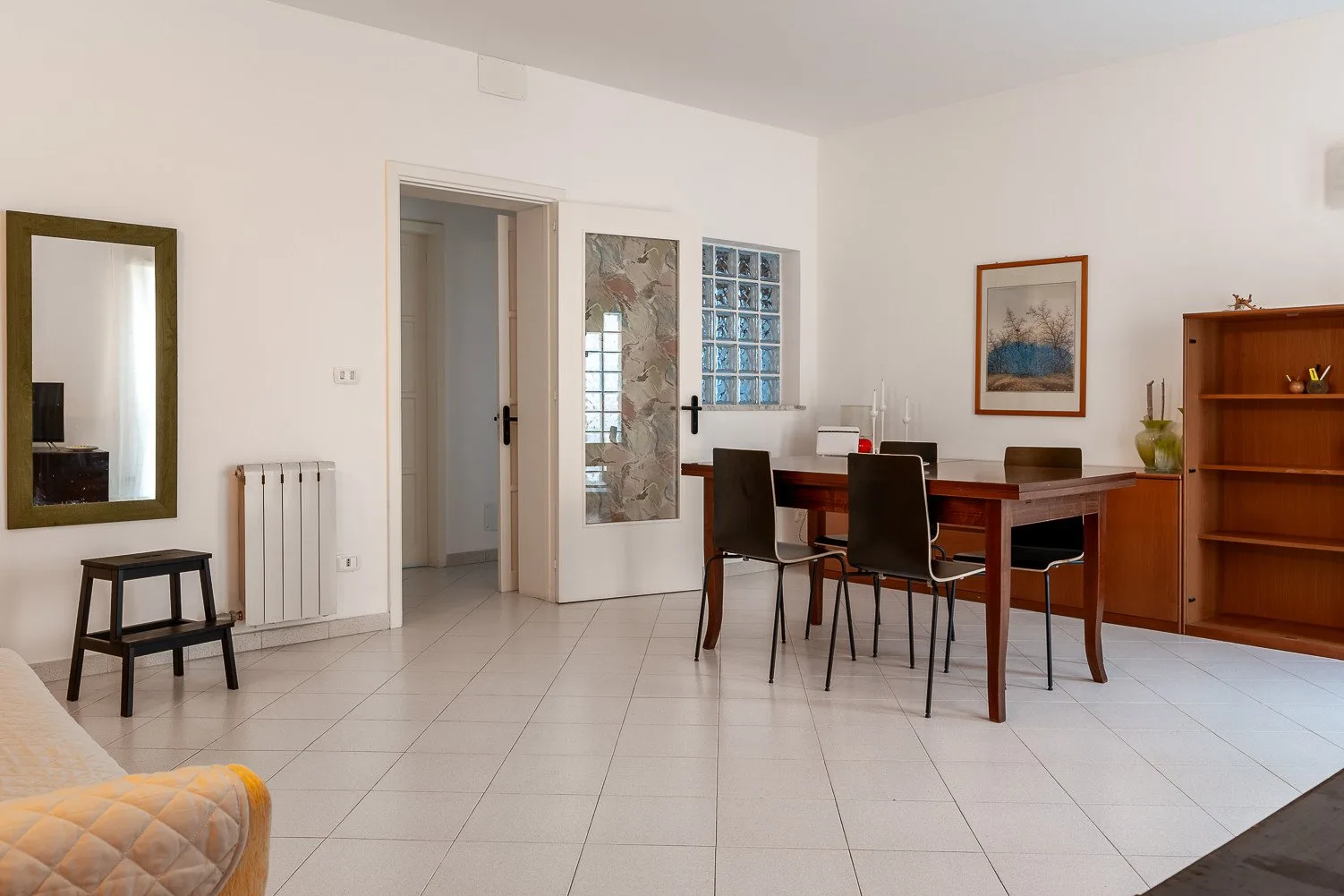 Un comedor con una mesa, sillas y una estantería de madera.