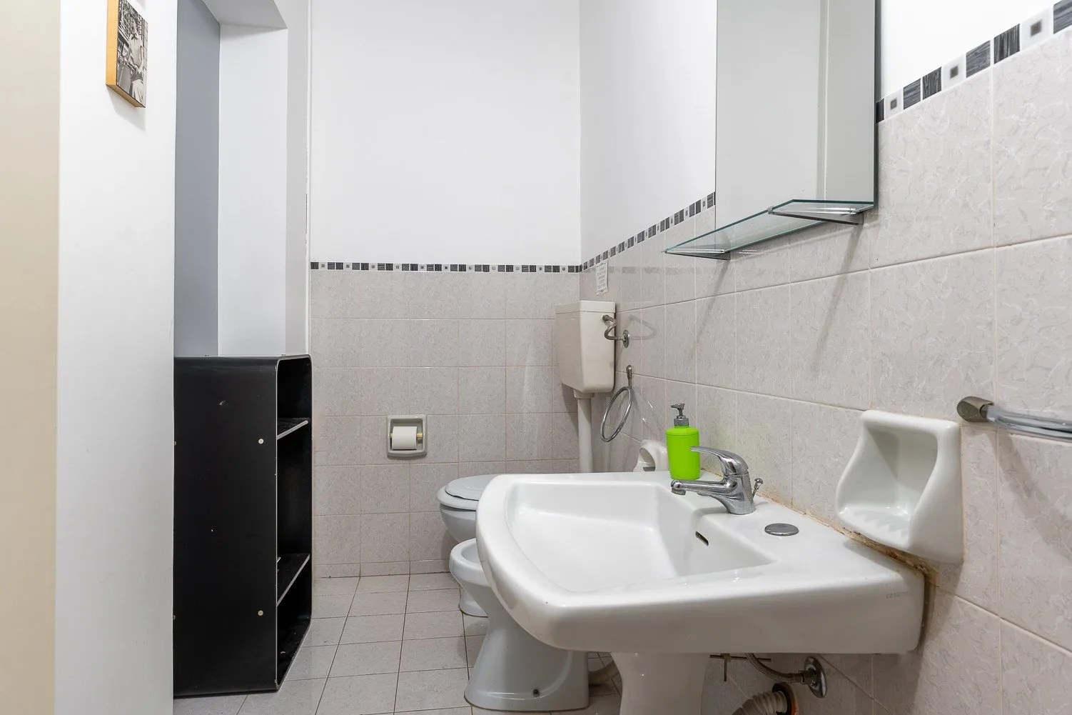 Un baño alicatado con un lavabo suspendido y un inodoro.