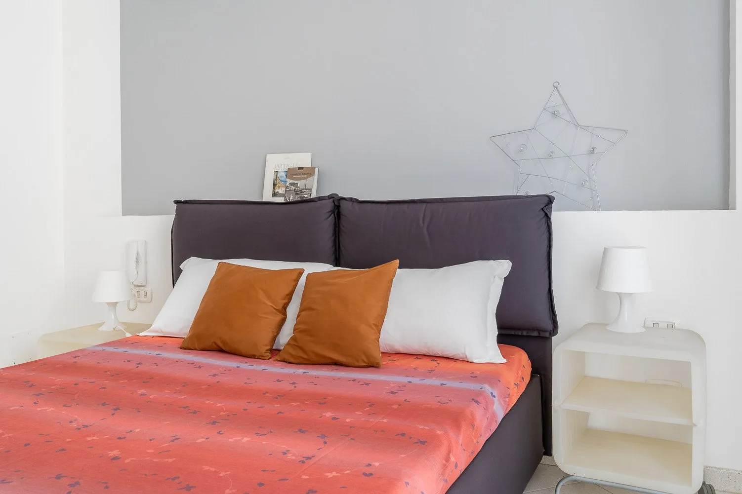 Un dormitorio con una cama vestida con ropa de cama coral y almohadas blancas.