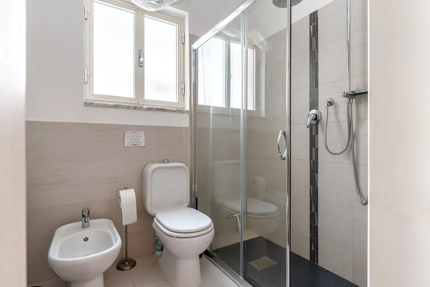 Un baño luminoso con inodoro, bidé y ducha de vidrio.