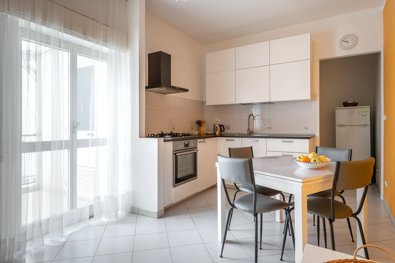 Una cocina luminosa con zona de comedor y una mesa junto a grandes ventanas.