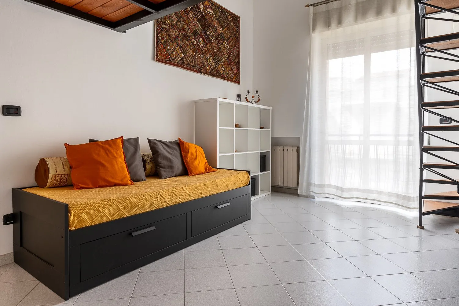 Una sala de estar luminosa con un diván y una gran ventana con cortinas.