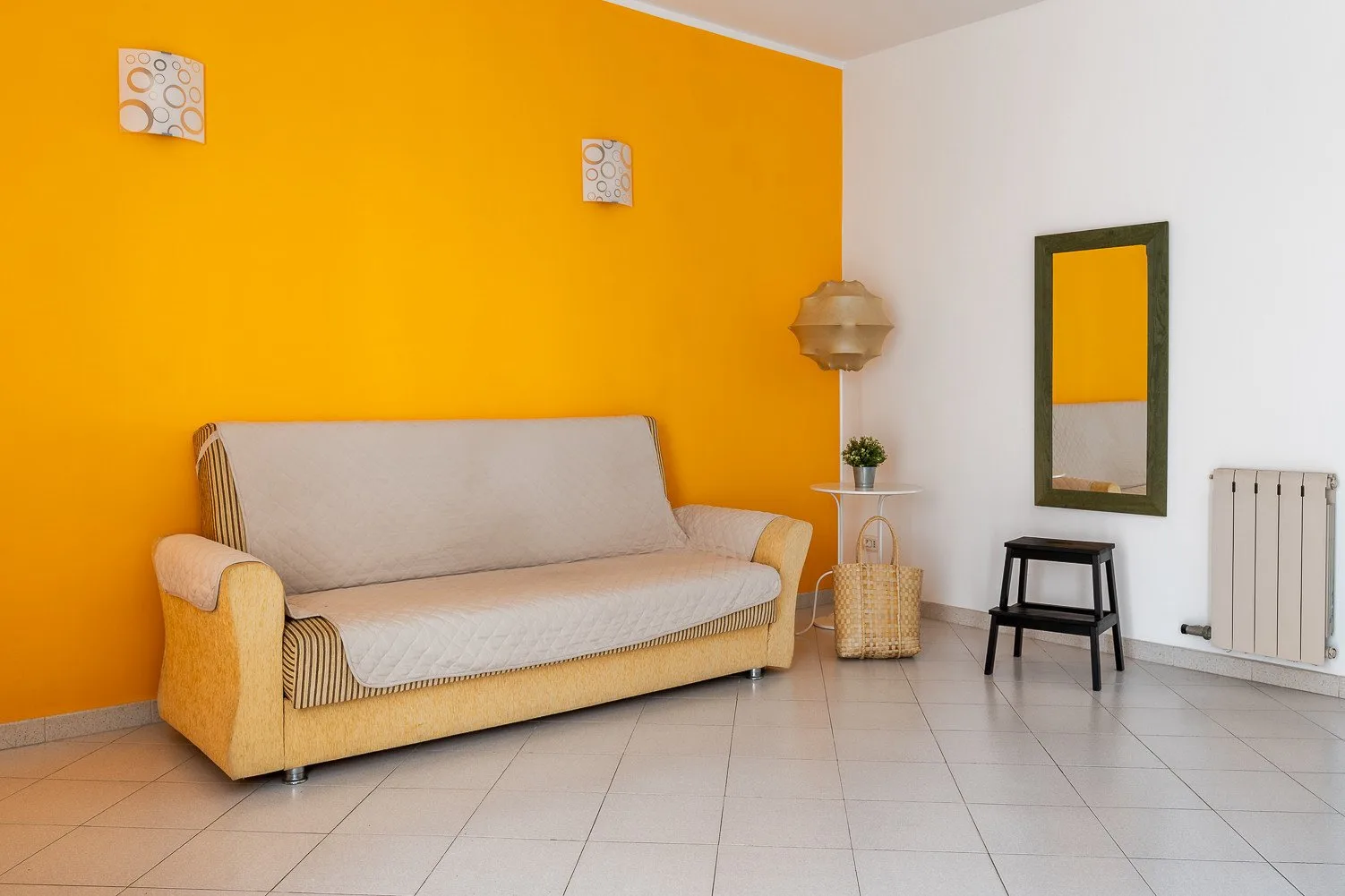 Una sala de estar con un sofá frente a una pared naranja brillante.