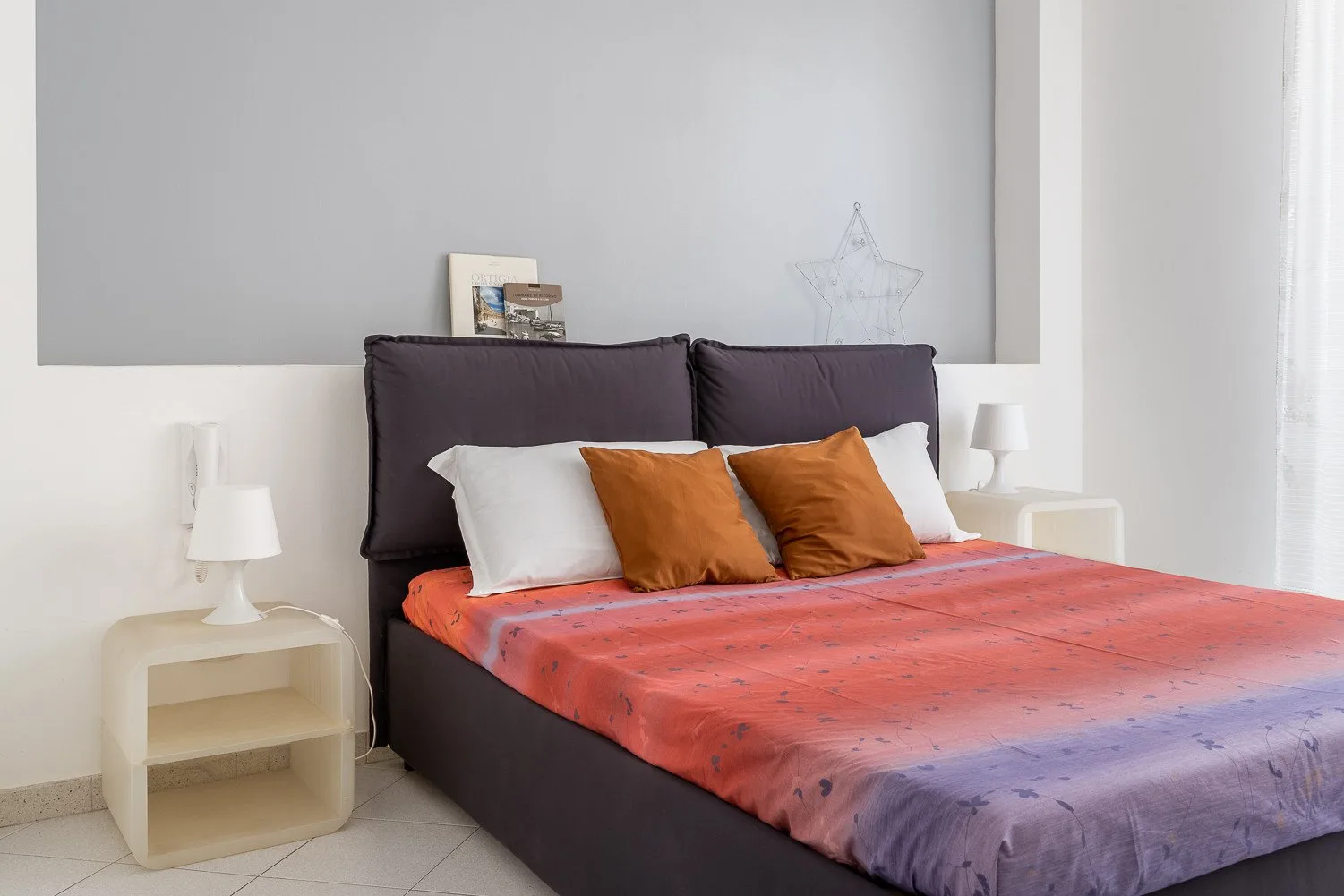 Un dormitorio con una cama vestida con ropa de cama naranja y morada.