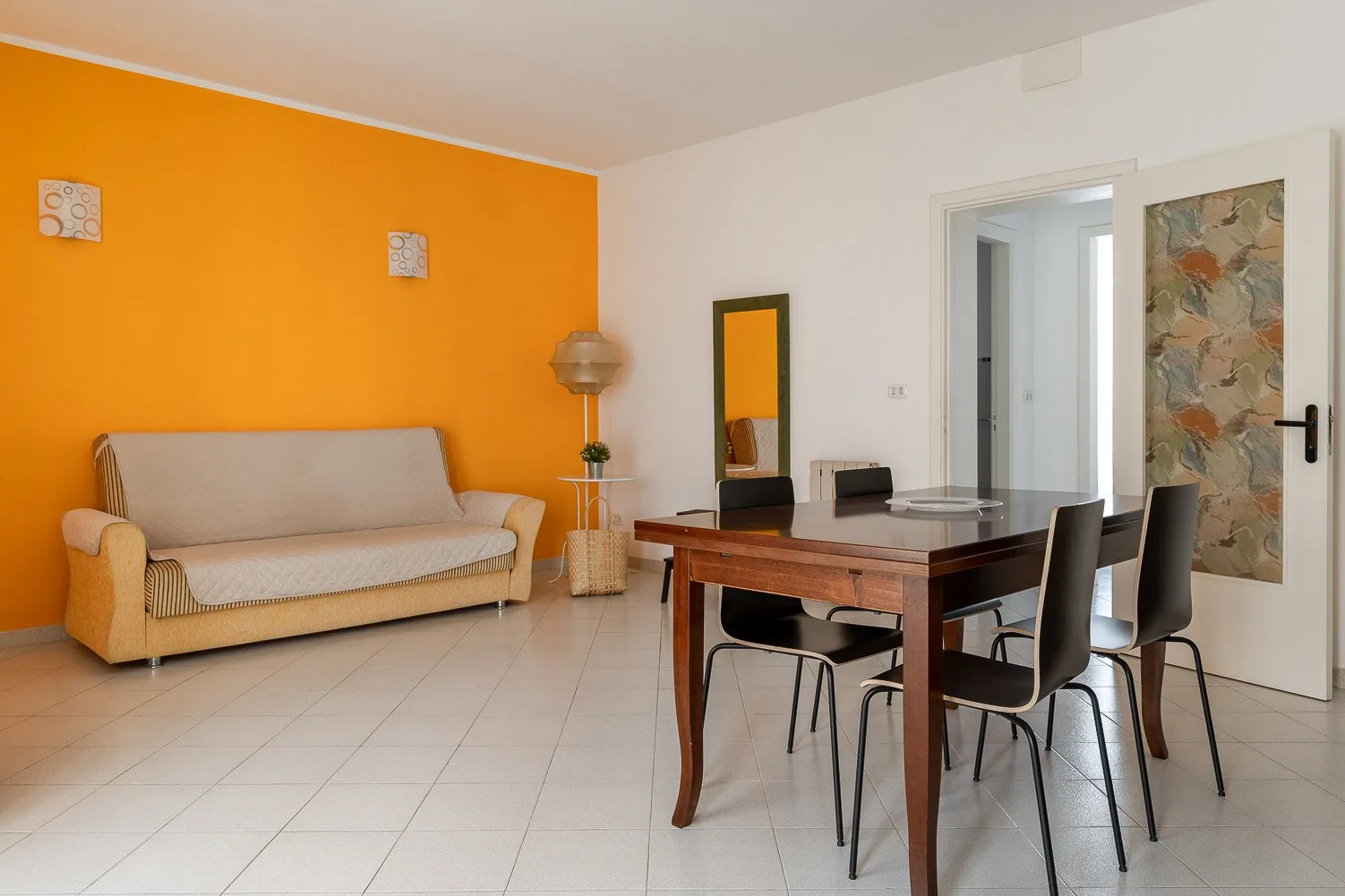 Un comedor con una mesa de madera y sillas junto a un sofá beige.