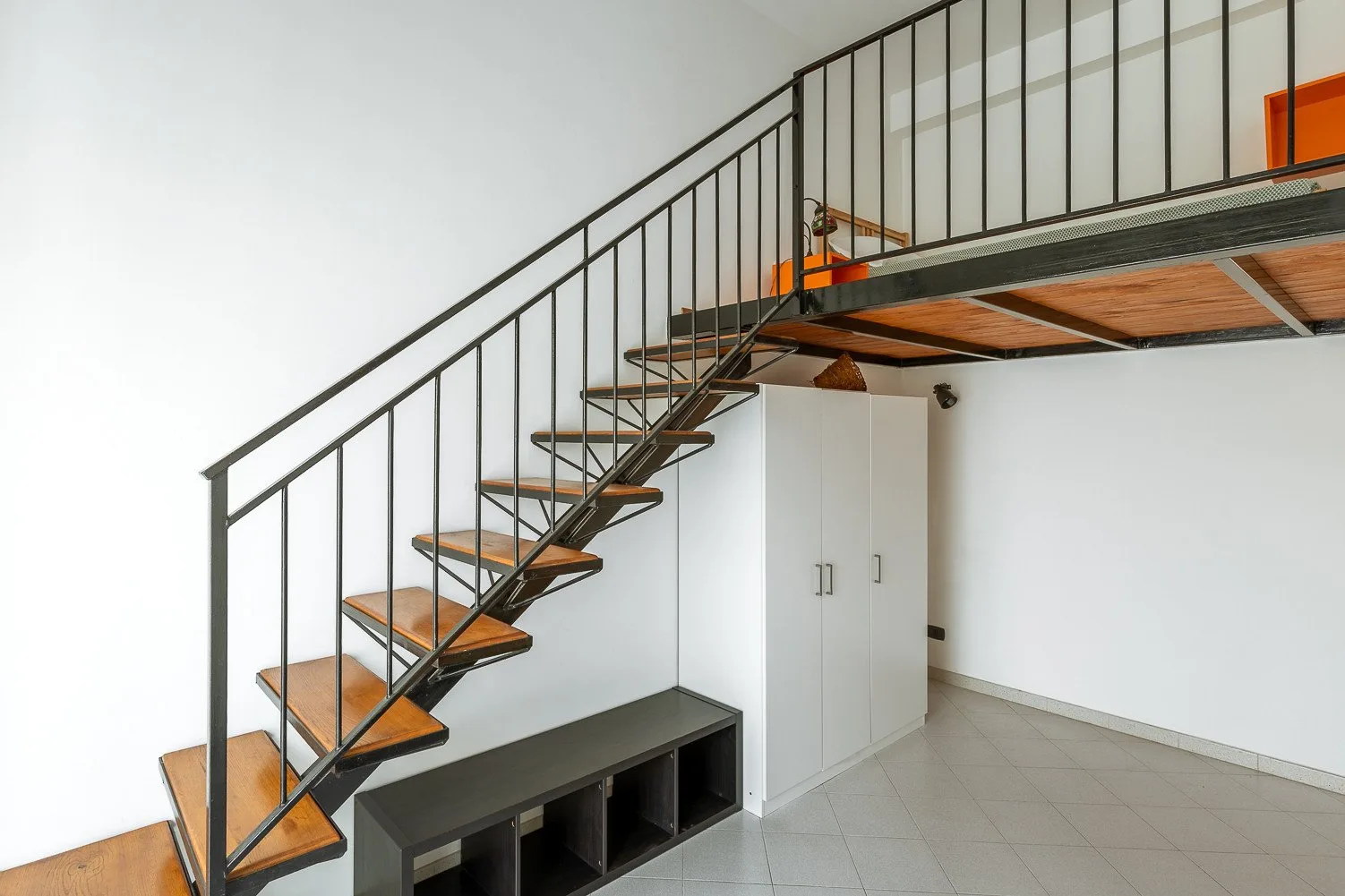 Un interior compacto con una escalera abierta que conduce a una plataforma elevada.