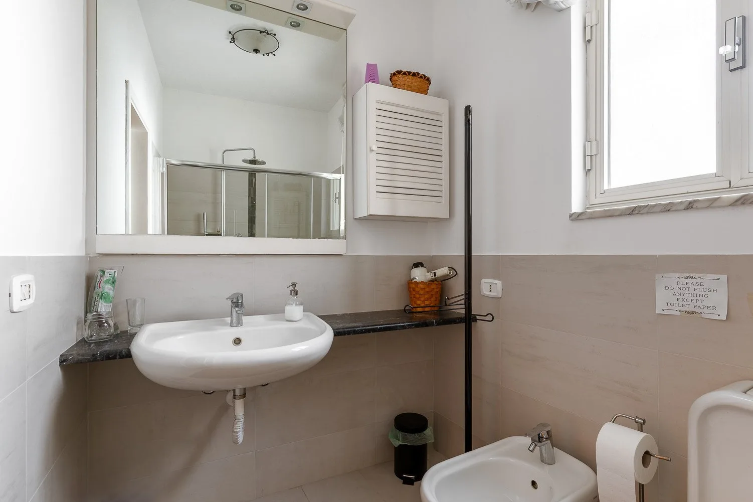 Un baño con un lavabo de pared y un espejo grande.