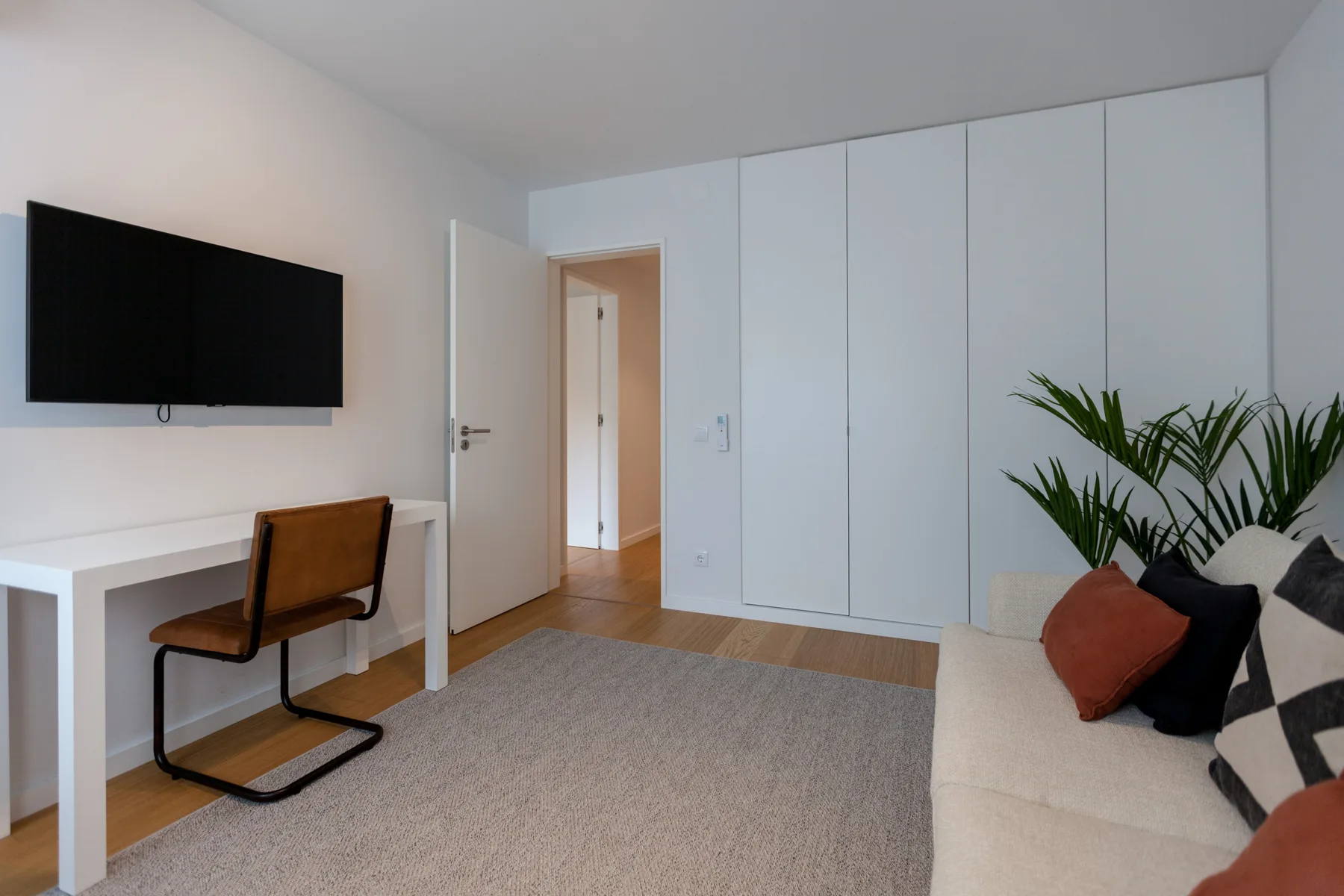 Una sala luminosa con escritorio, televisión y asientos.