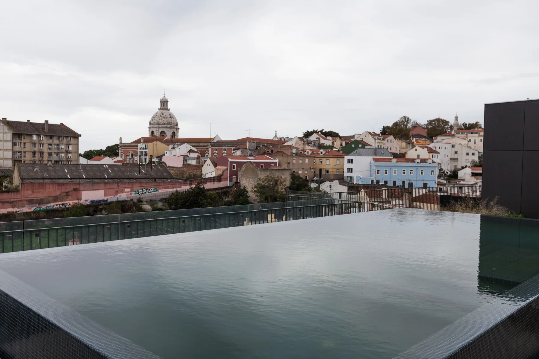 Una terraza en la azotea da a los tejados de la ciudad, con una piscina reflectante en primer plano.