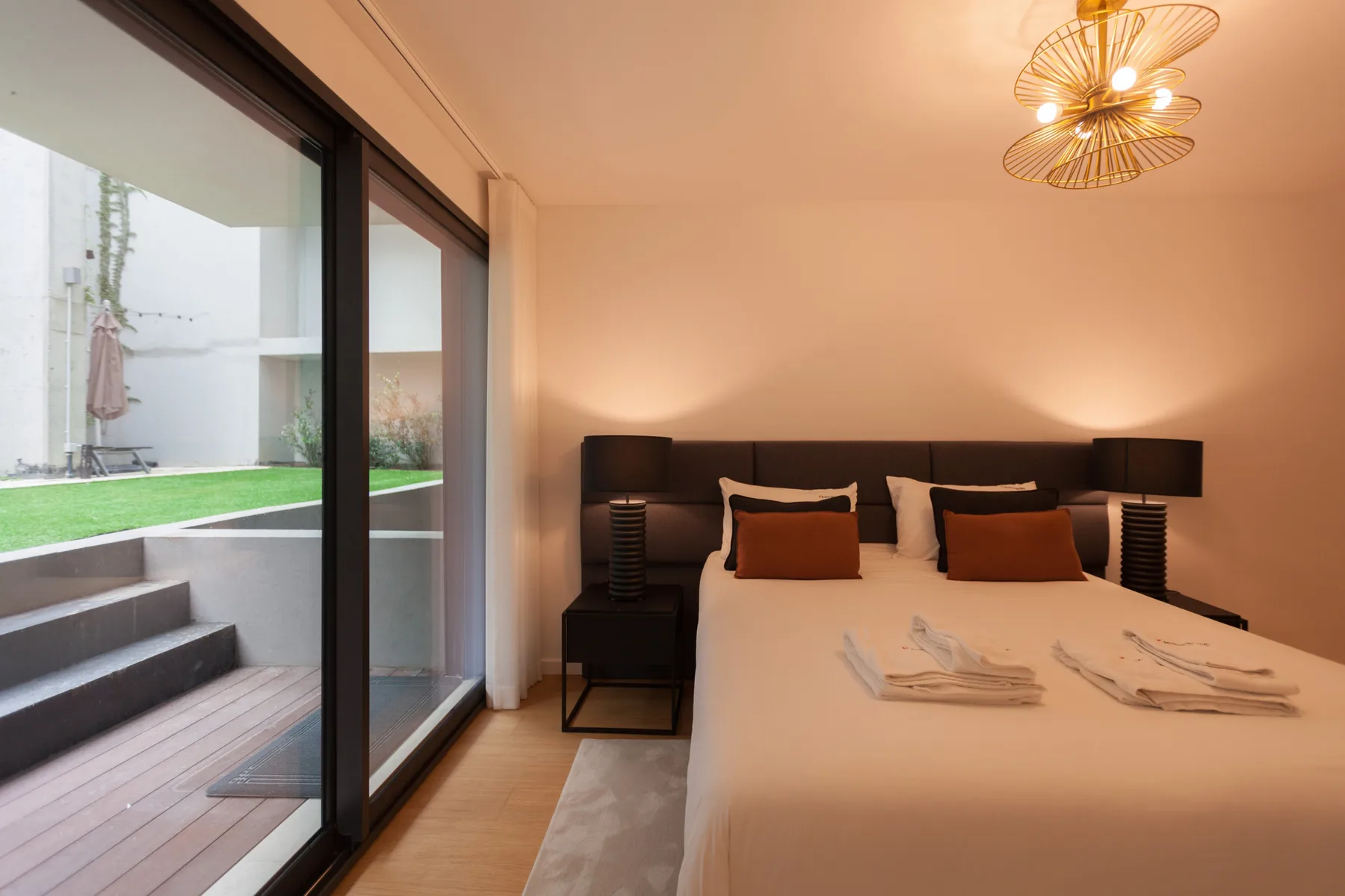 Un dormitorio con una cama junto a puertas corredizas de vidrio que dan a un pequeño patio.