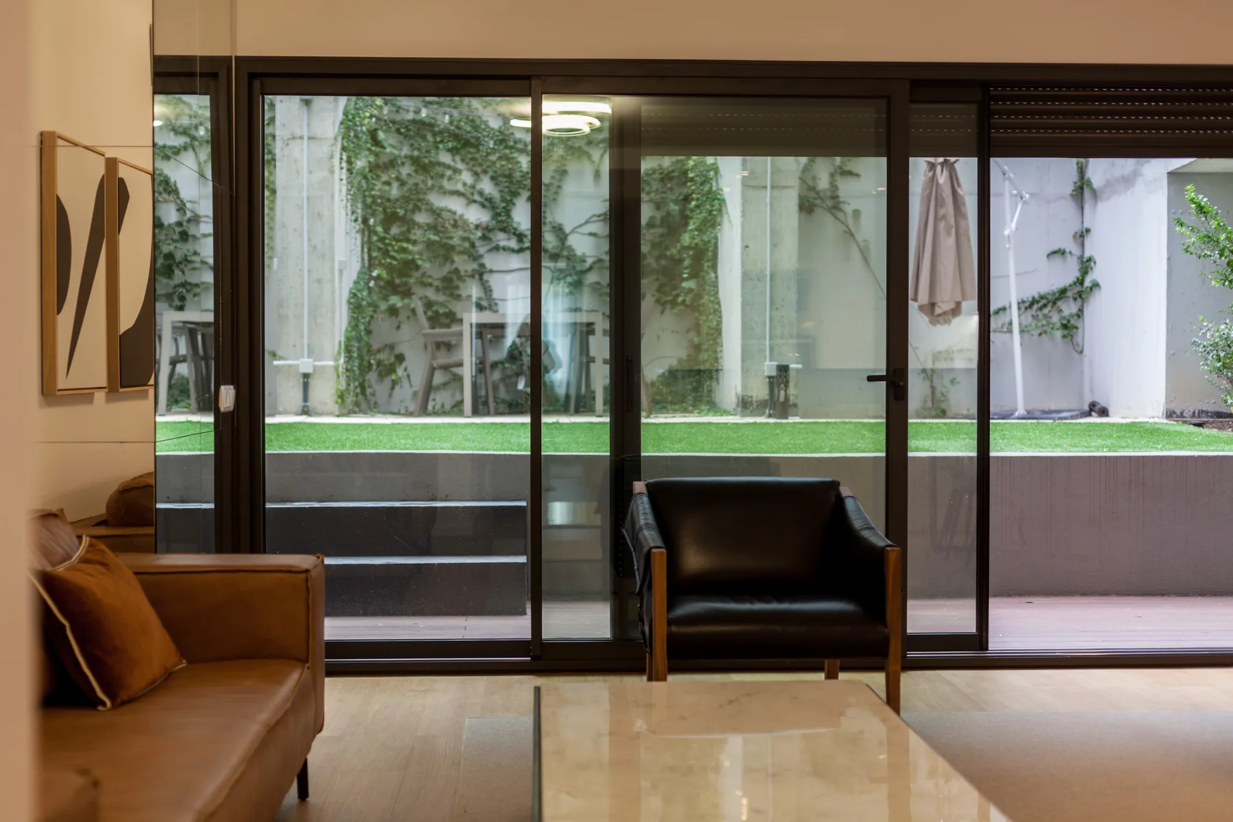 Una sala de estar con asientos junto a grandes puertas de vidrio que dan a un patio.