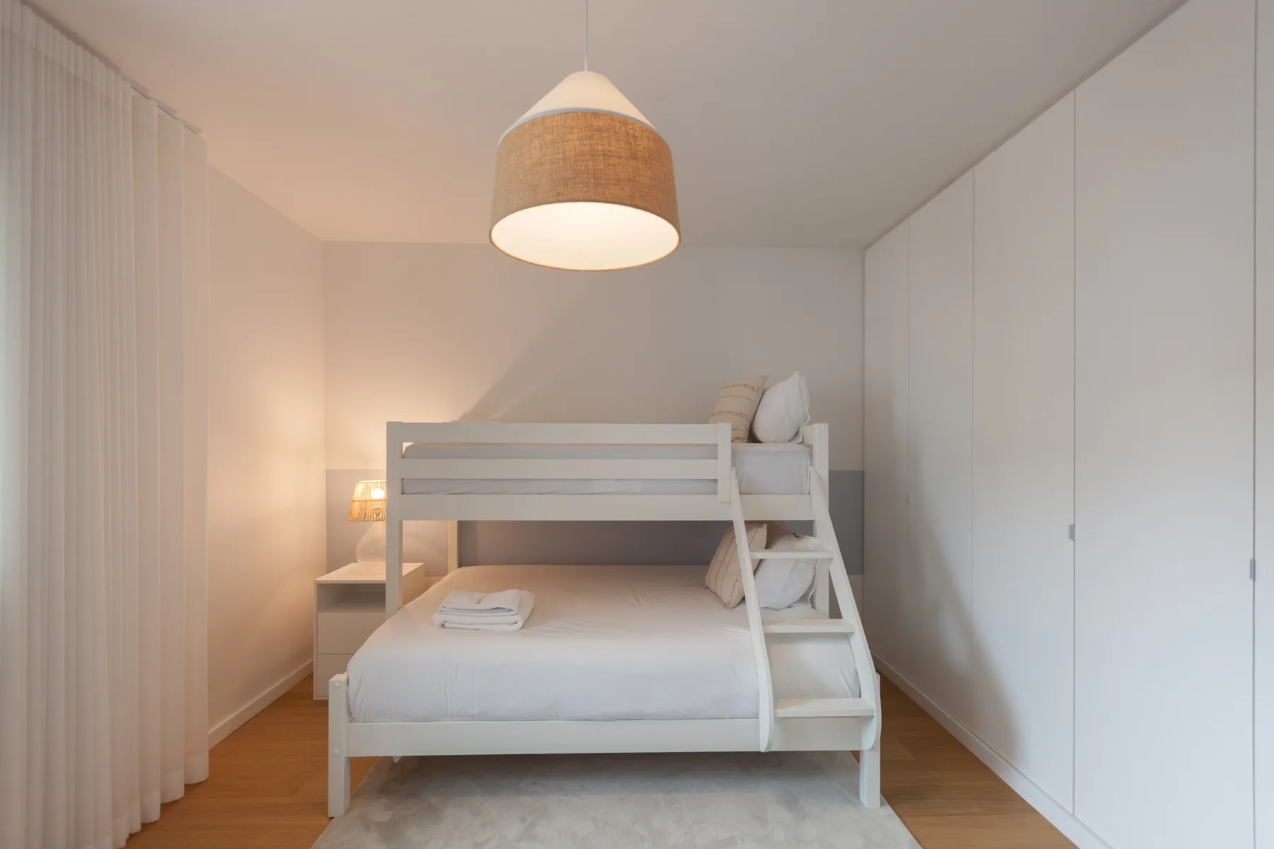 Un dormitorio luminoso con una litera blanca y armarios empotrados.