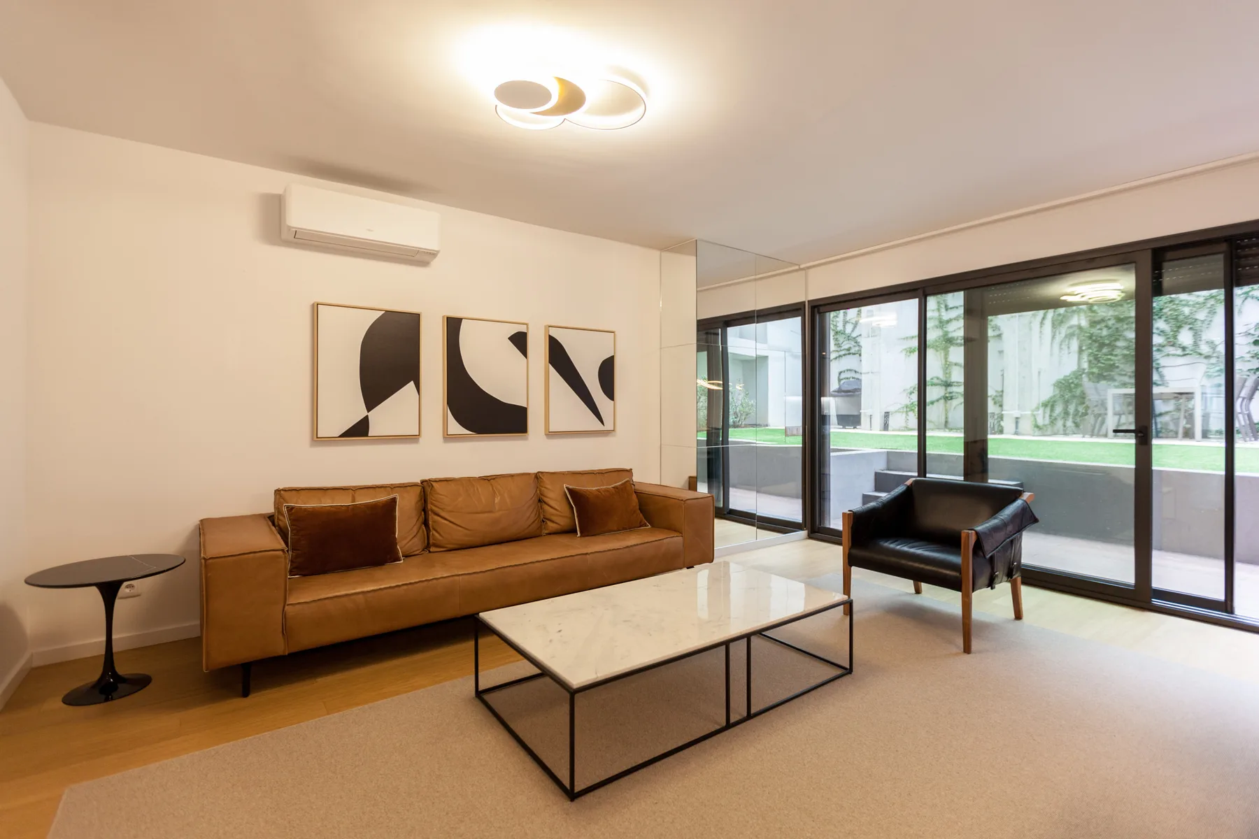 Sala de estar con asientos y una mesa de centro junto a grandes ventanas.