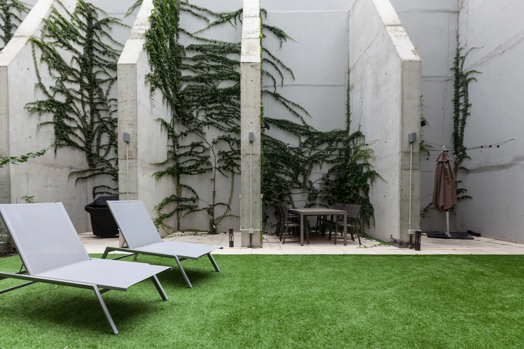 Una terraza al aire libre con asientos, vegetación y una pequeña zona de comedor.