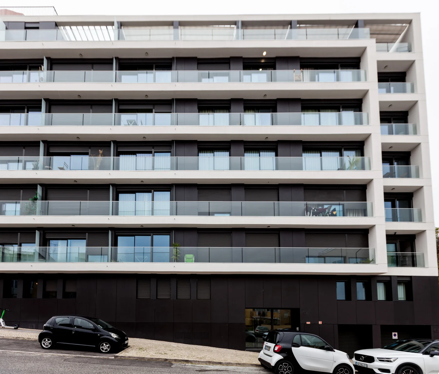 Un edificio de apartamentos moderno con filas de balcones sobre el estacionamiento a nivel de calle.