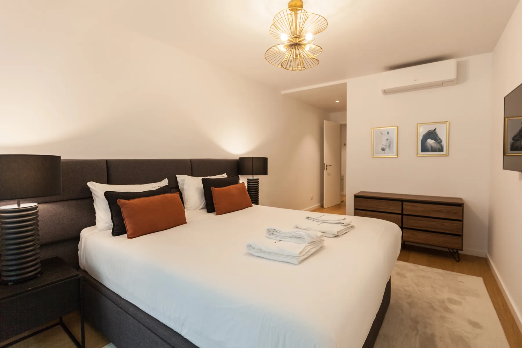Dormitorio con una cama bien hecha y cuadros enmarcados en la pared.