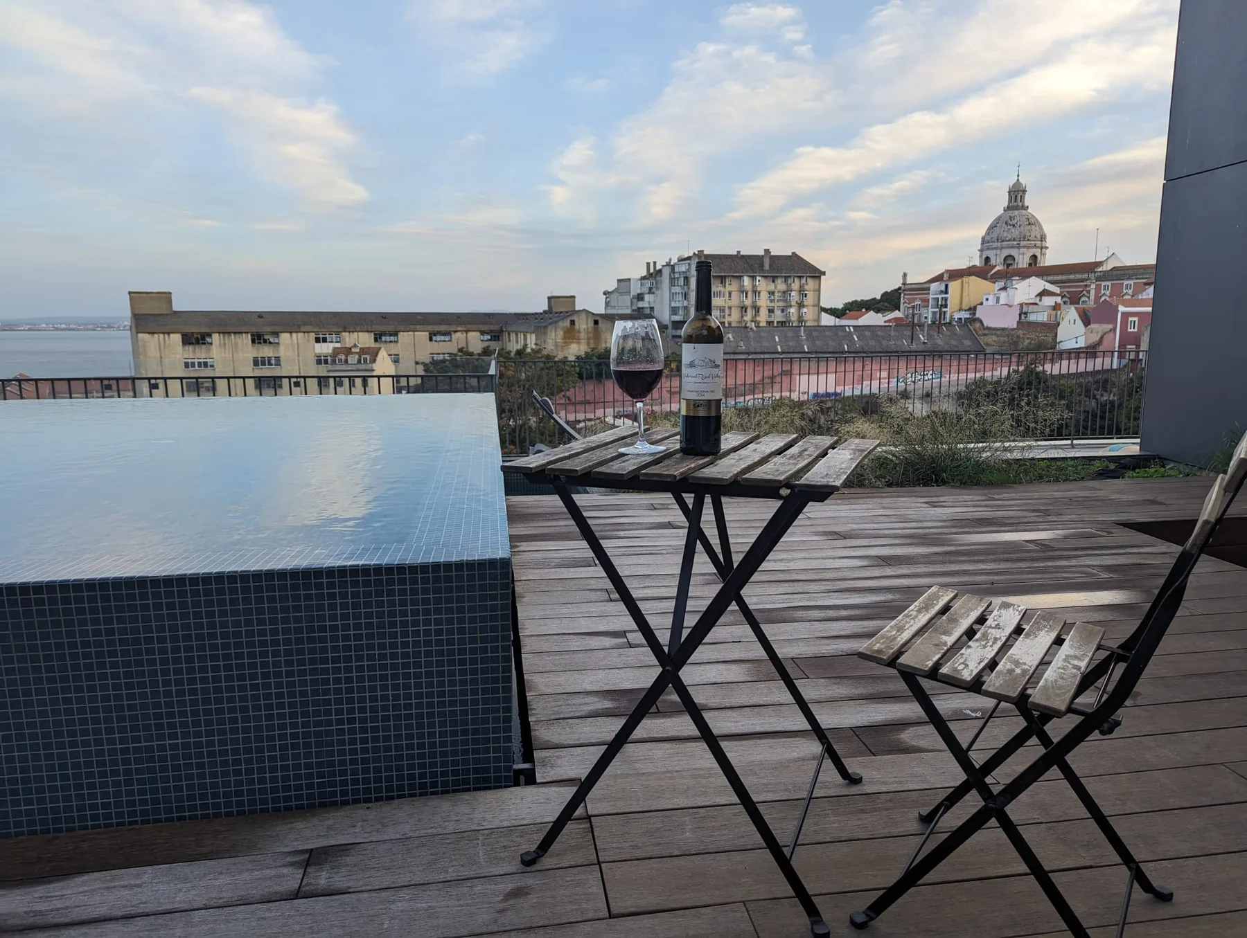 Una terraza en la azotea tiene una mesa pequeña y asientos con vistas a los tejados de la ciudad.