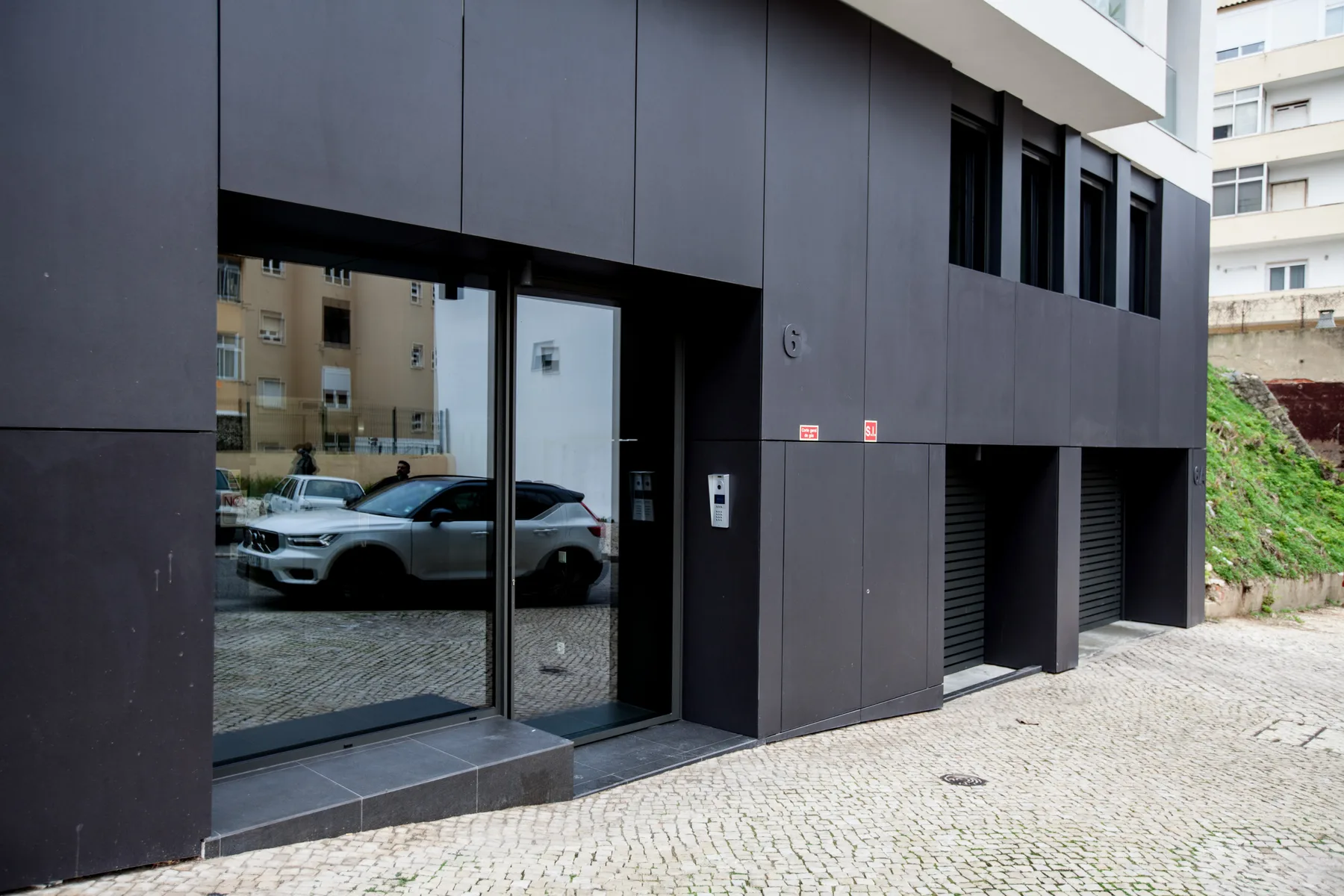 Entrada de un edificio moderno con puertas de vidrio y una acera pavimentada.
