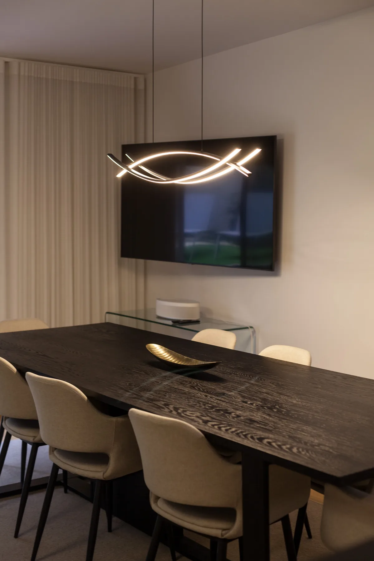 Un comedor con una mesa larga y una luminaria encendida.