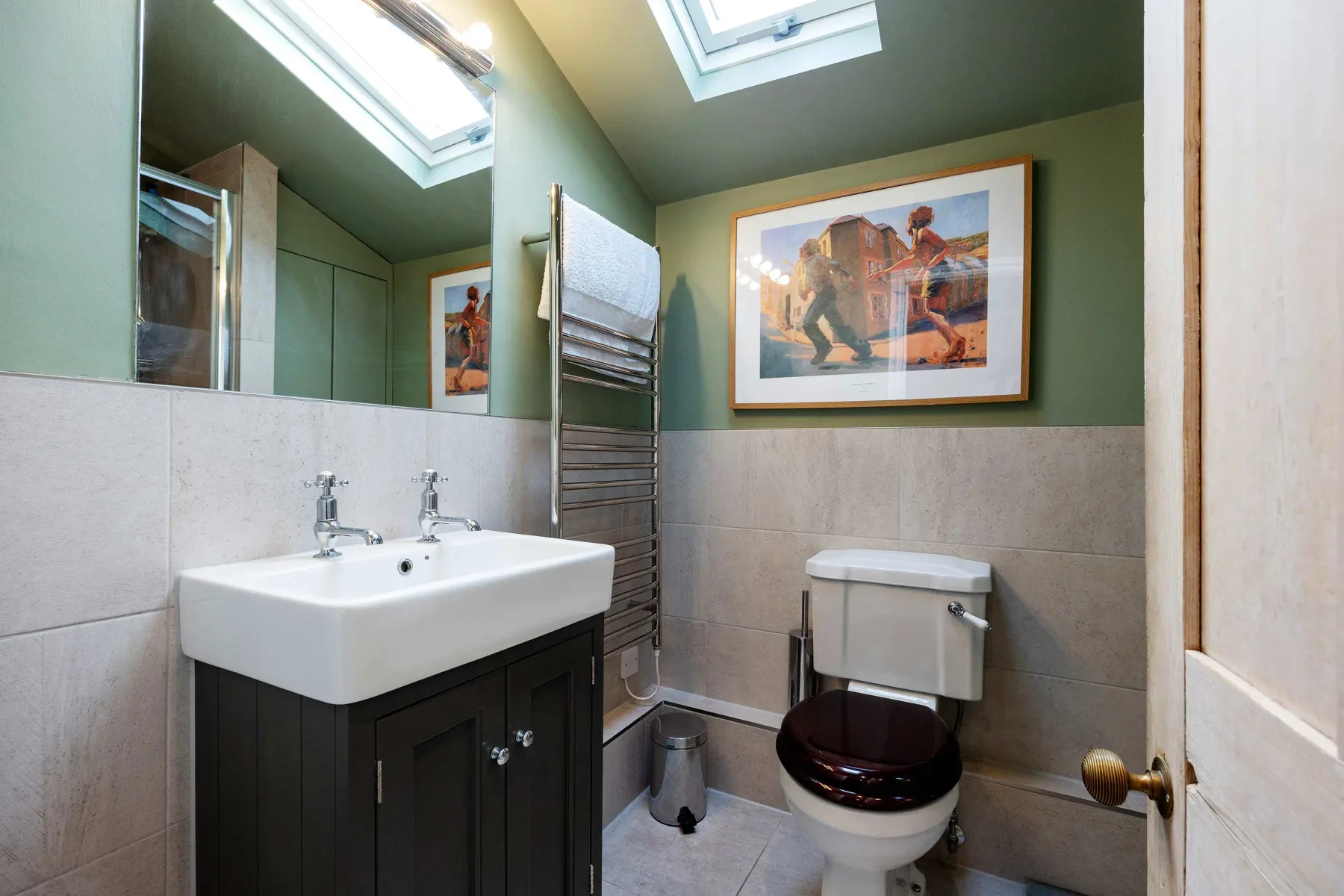 Un baño con lavabo, inodoro y una obra enmarcada en la pared.