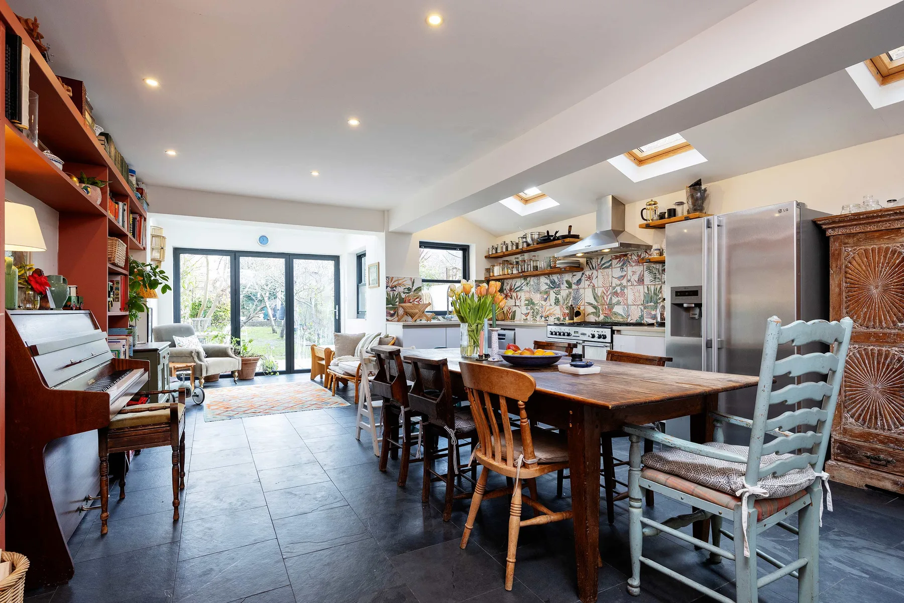 Una amplia cocina y comedor con una larga mesa de madera y ventanas.