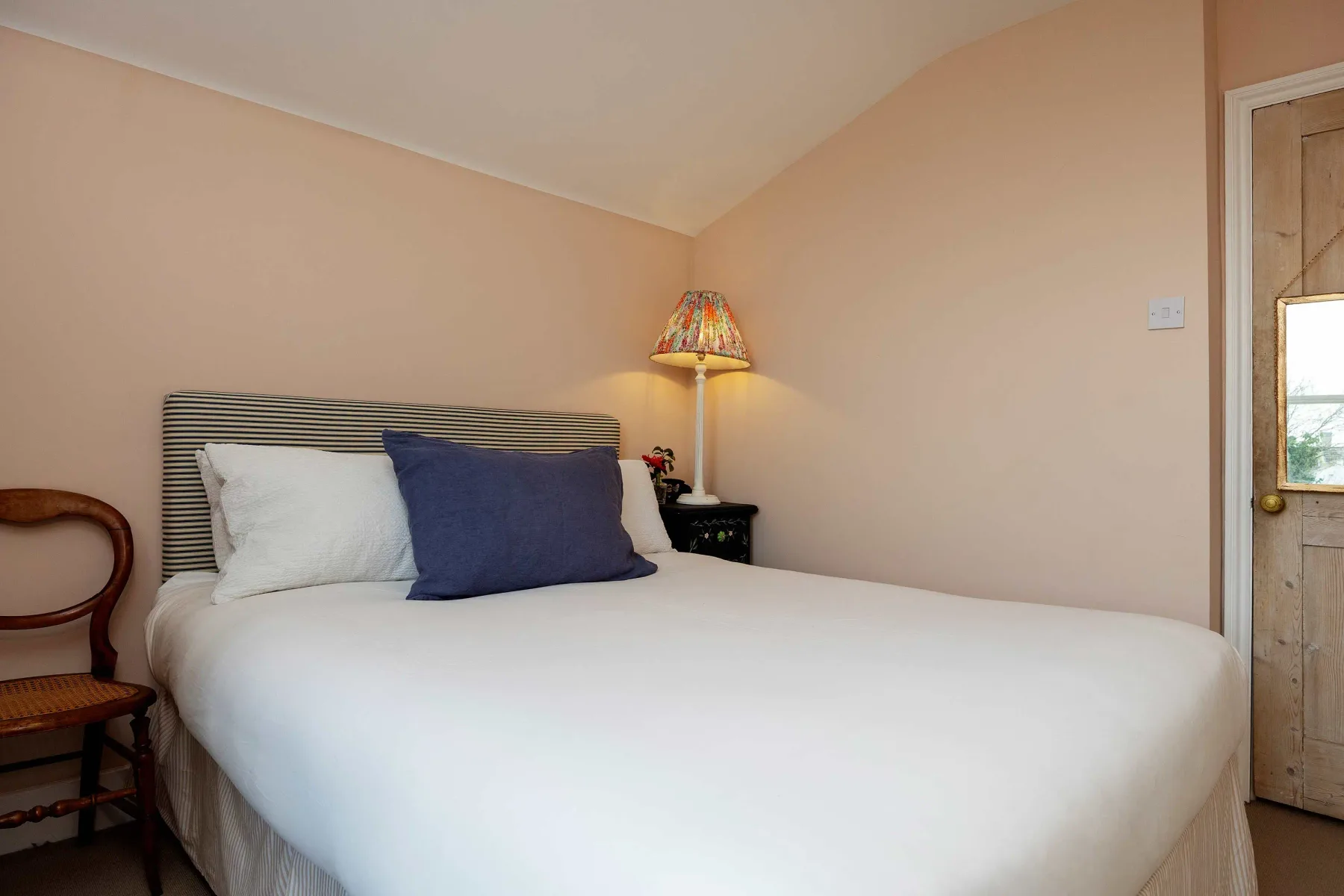 Un dormitorio con una cama bien arreglada y una lámpara de noche.