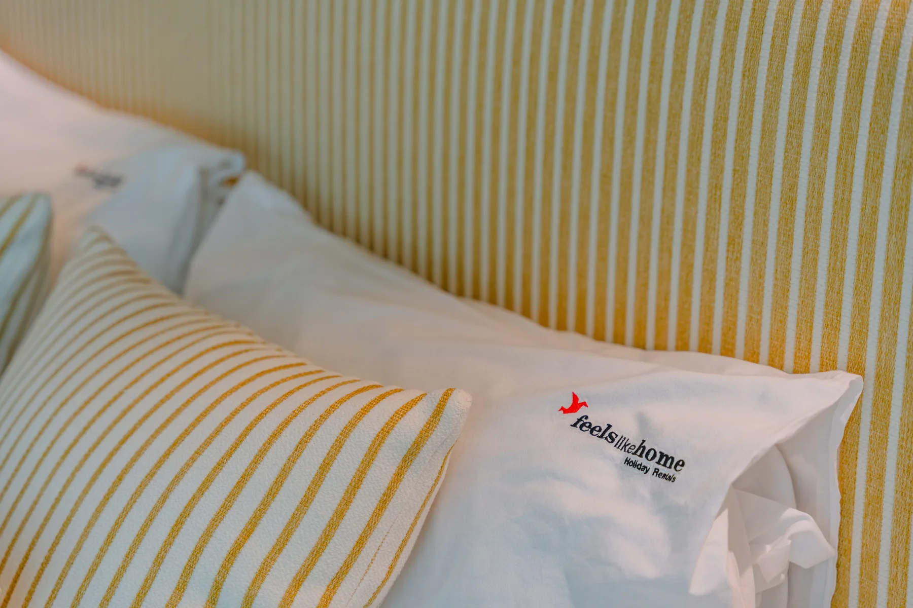 A bed with white pillows and striped bedding.