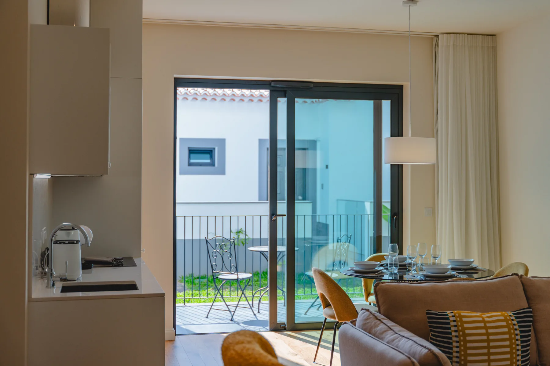 A living and dining area opens onto a balcony through sliding glass doors.