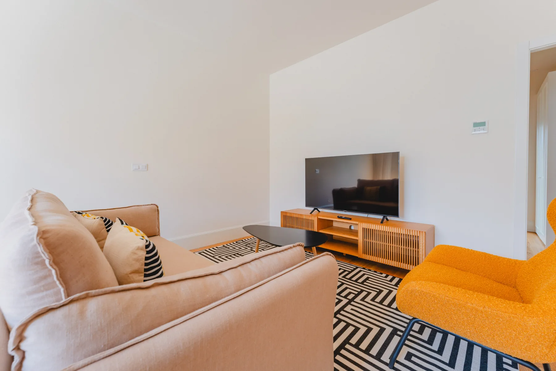 A living room with a television, seating, and a geometric-patterned rug.