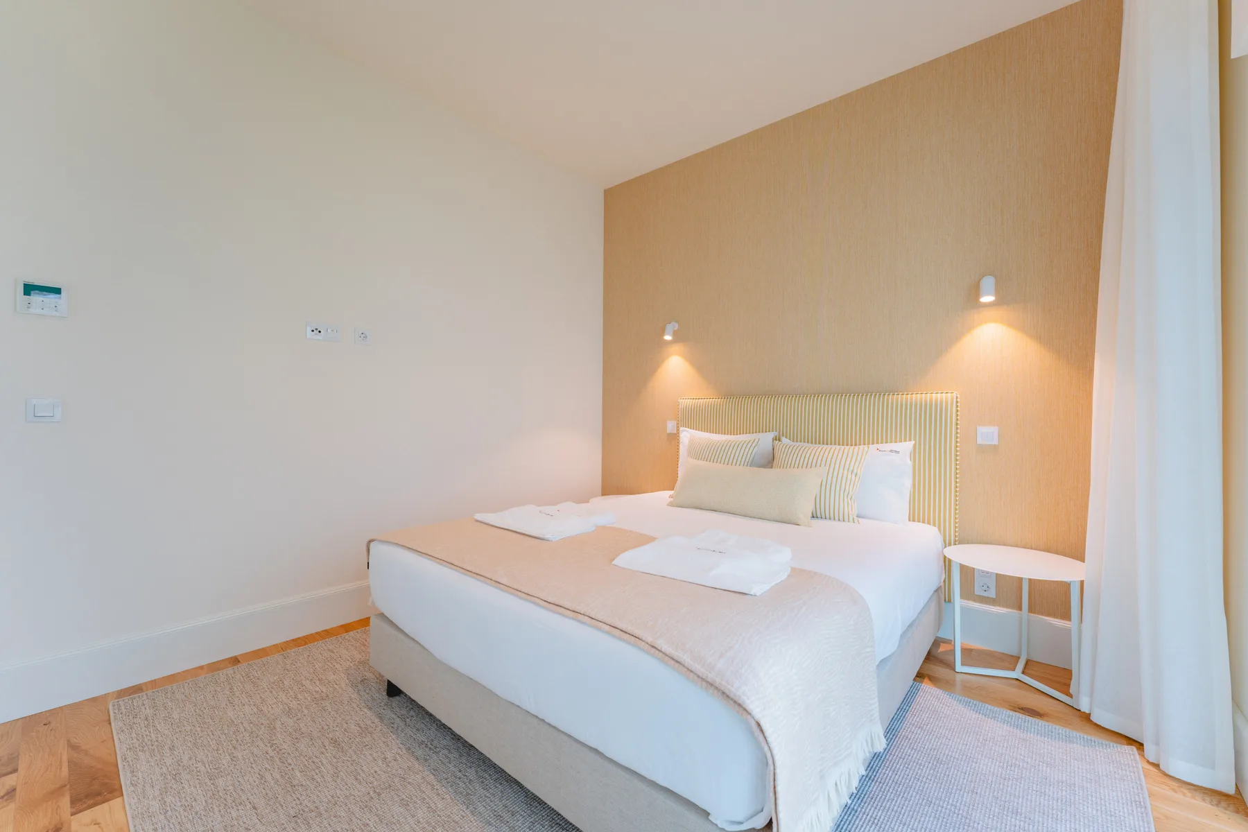 A bedroom with a double bed, bedside tables, and a rug.