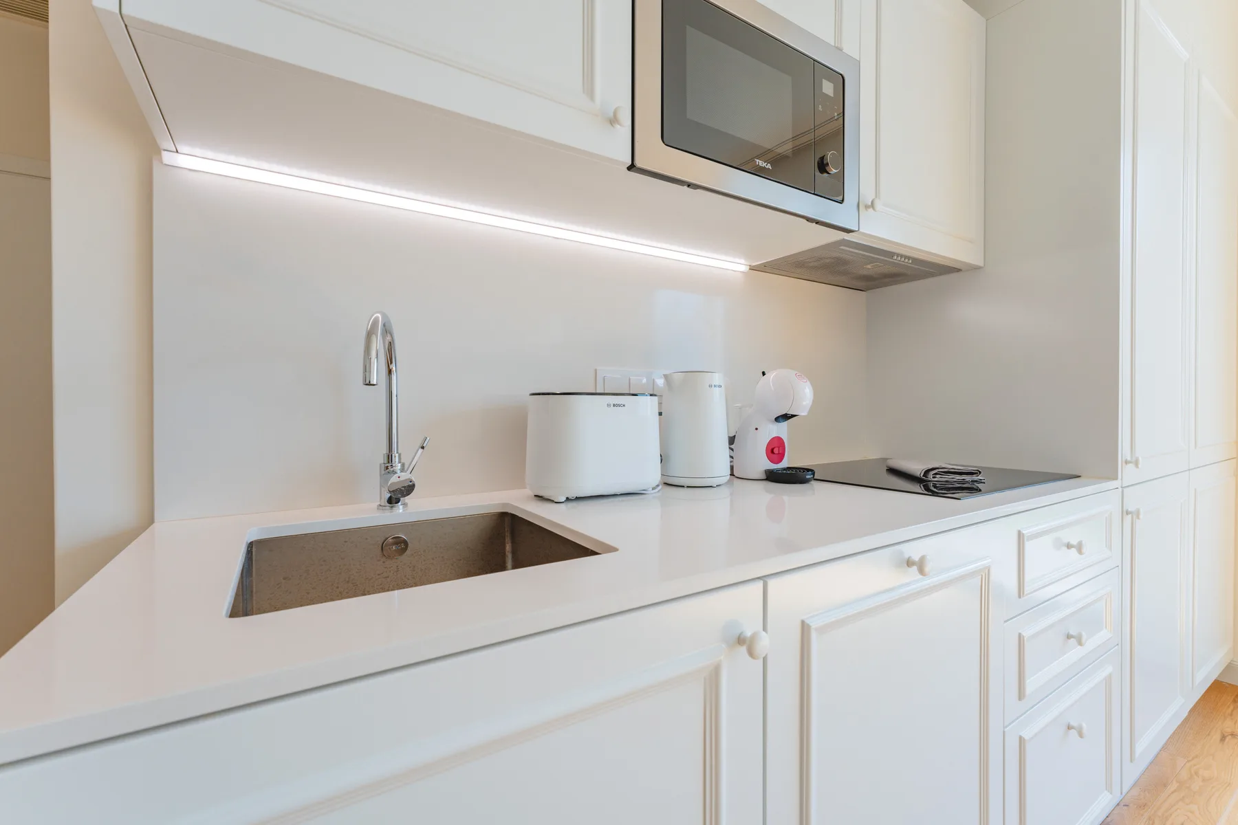 A bright kitchen with a sink, countertop appliances, and a cooktop.