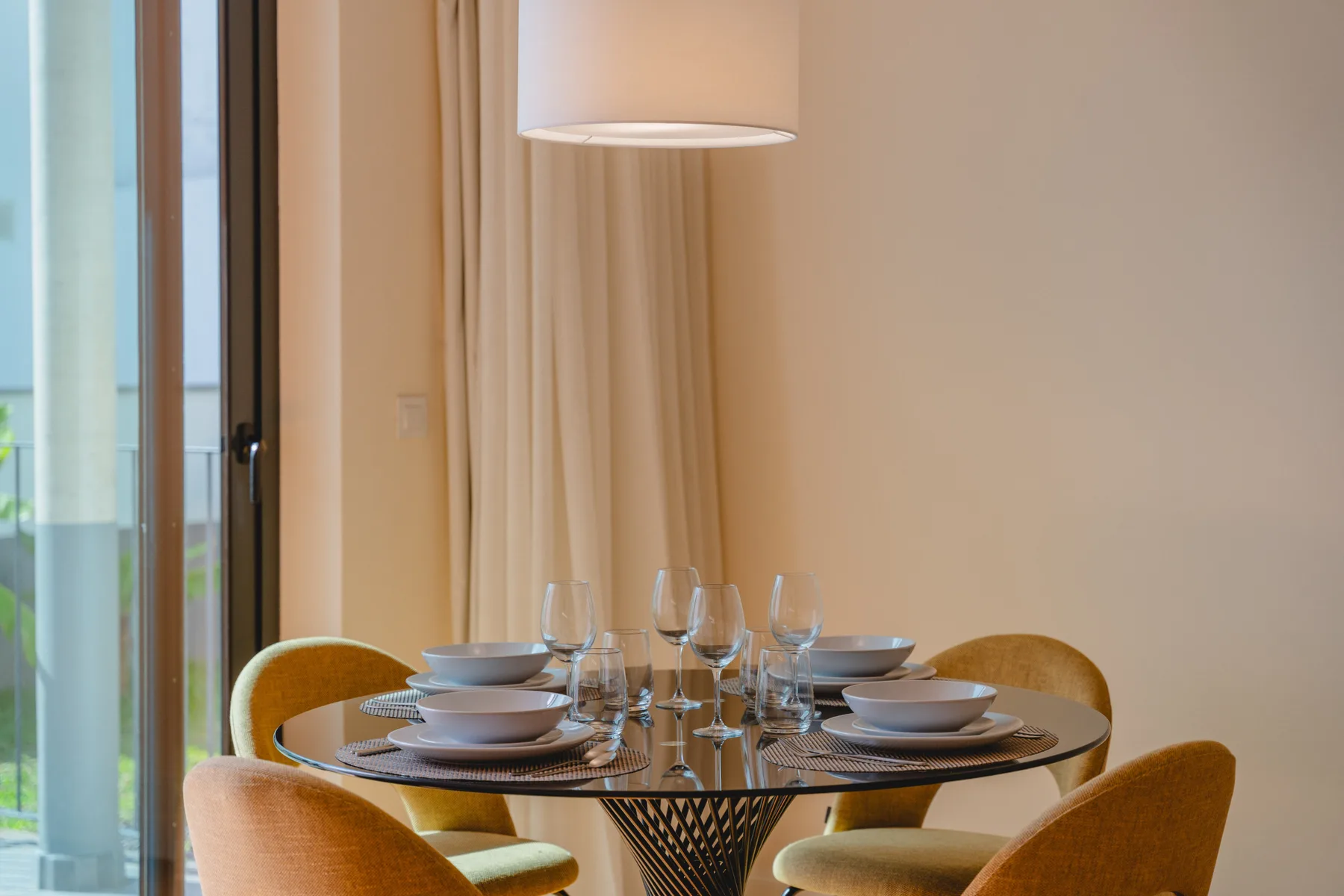 A dining area with a set table and chairs beside a glass door.