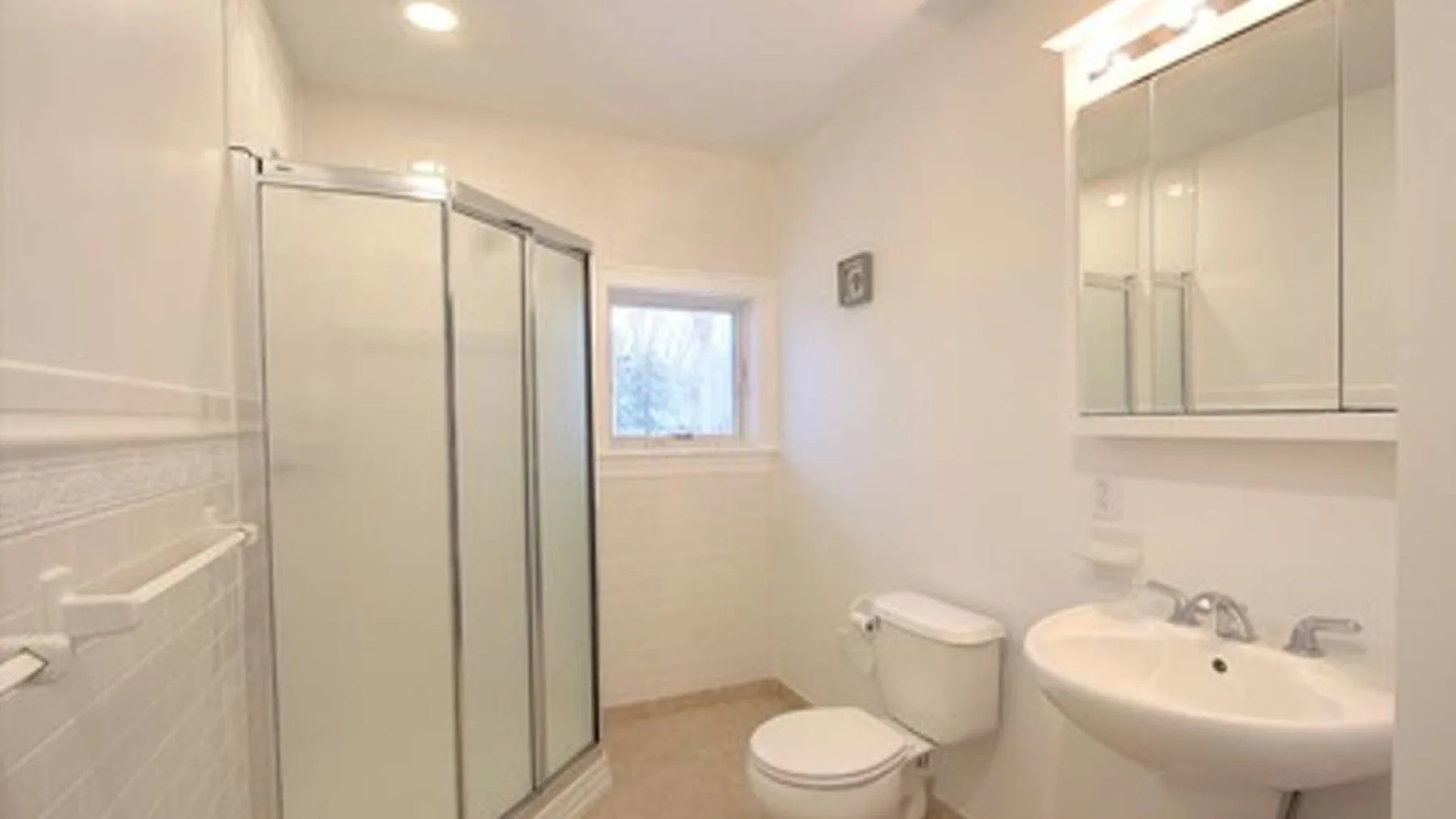 A bathroom with a glass shower, toilet, and sink.