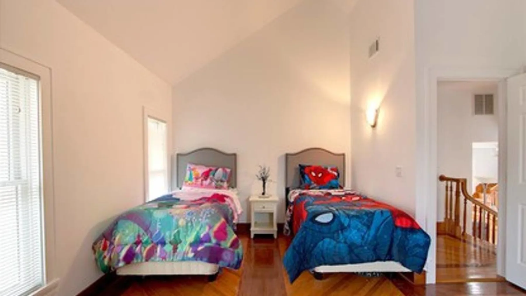 A bright bedroom with two single beds and colorful bedding.