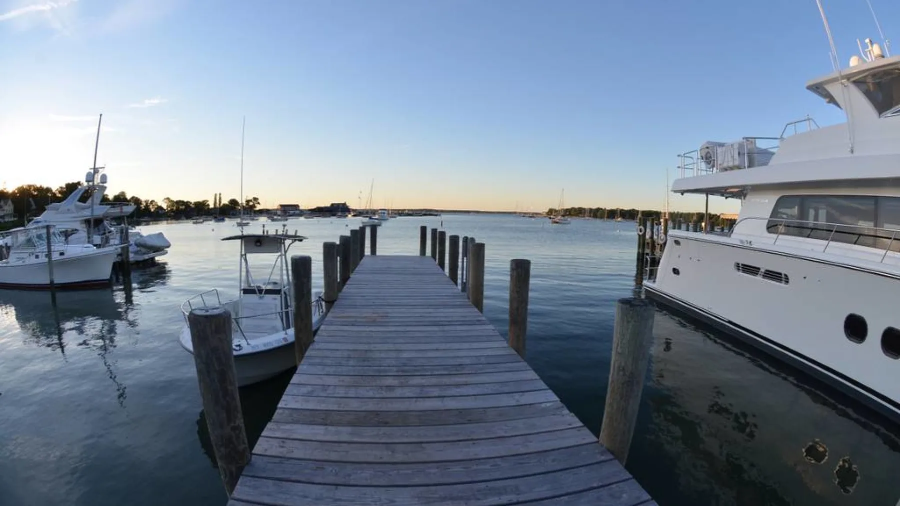 A wooden dock extends into calm water beside several moored boats.