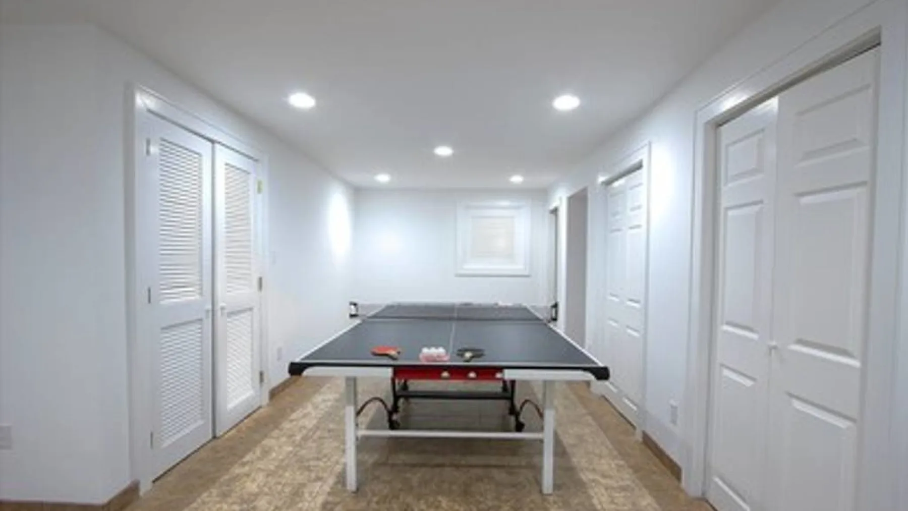A bright indoor recreation room with a ping-pong table.