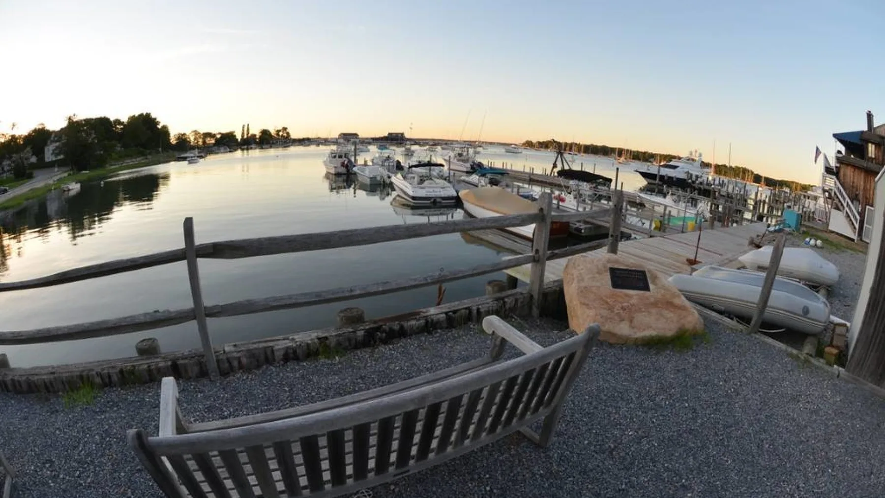 A marina with boats moored along the water beside a gravel path.