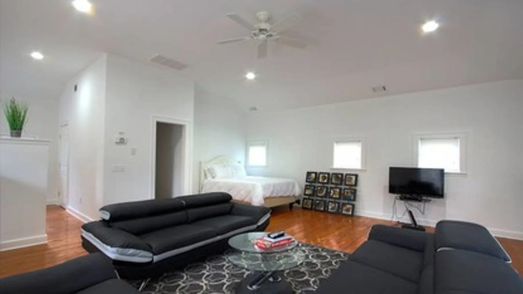 A bright living area with dark seating, a glass coffee table, and a television.