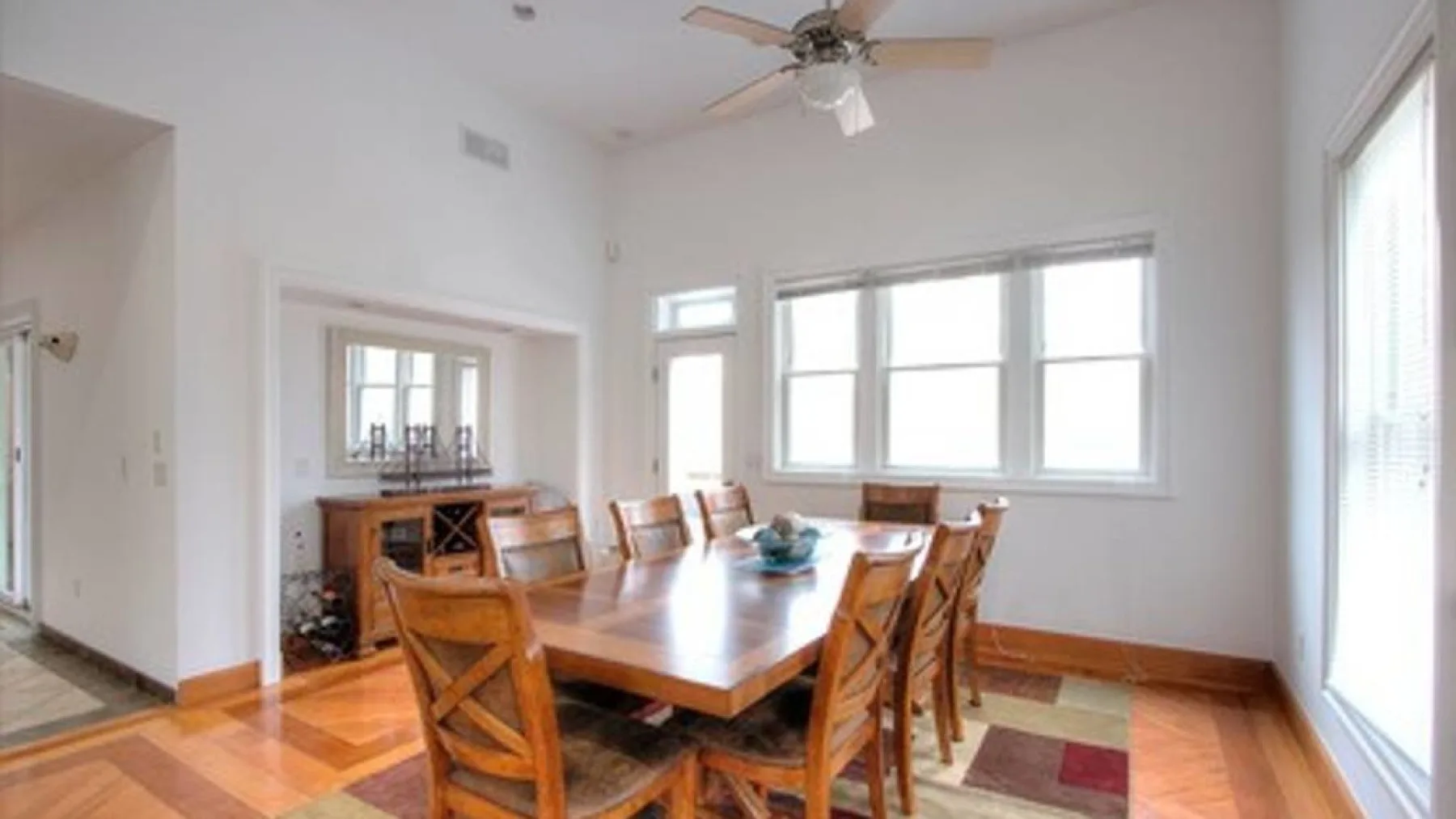 A bright dining room with a wooden table and large windows.